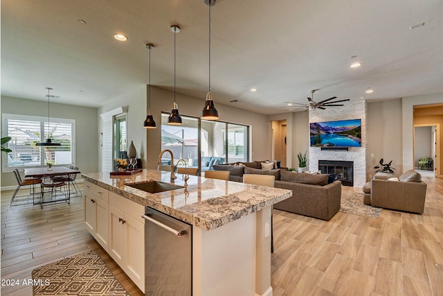 kitchen with white cabinetry, a wealth of natural light, light stone countertops, and a center island with sink