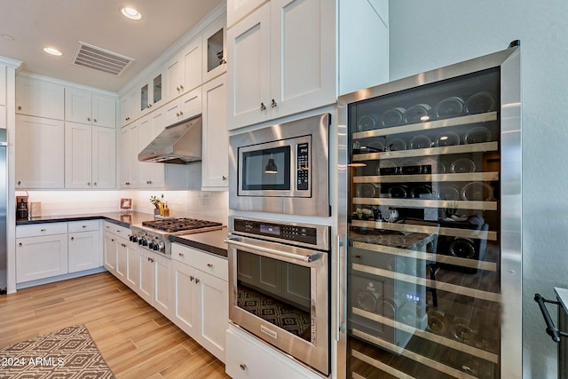 kitchen featuring stainless steel appliances, light hardwood / wood-style floors, white cabinetry, and wine cooler