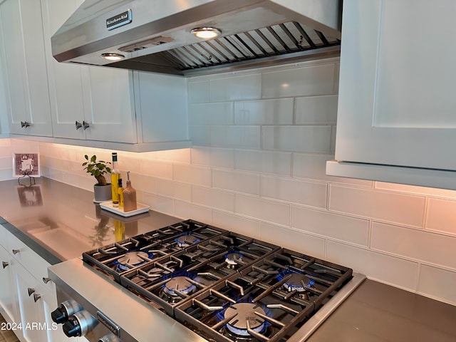 kitchen with white cabinets, stainless steel gas stovetop, decorative backsplash, and exhaust hood