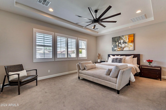 carpeted bedroom featuring ceiling fan and a tray ceiling