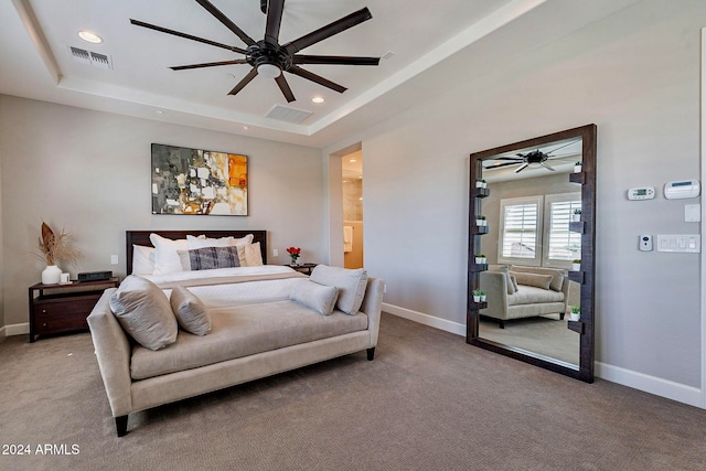 carpeted bedroom with a tray ceiling, ceiling fan, and ensuite bathroom