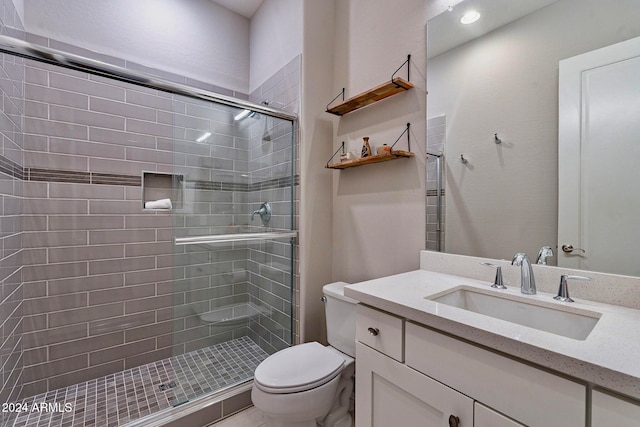 bathroom featuring a shower with shower door, vanity, and toilet