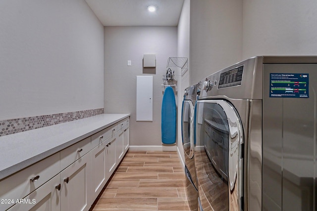 laundry area featuring cabinets, light wood-type flooring, and independent washer and dryer