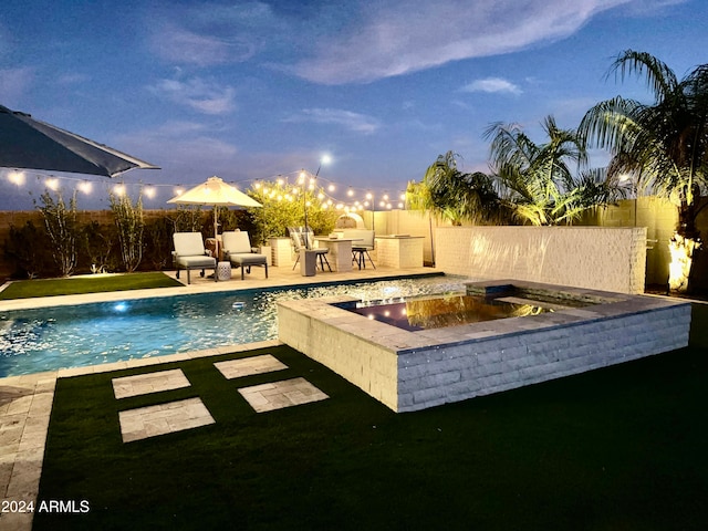 pool at dusk featuring a patio area and a lawn