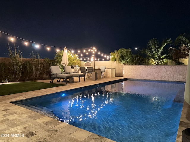 pool at twilight featuring a patio area