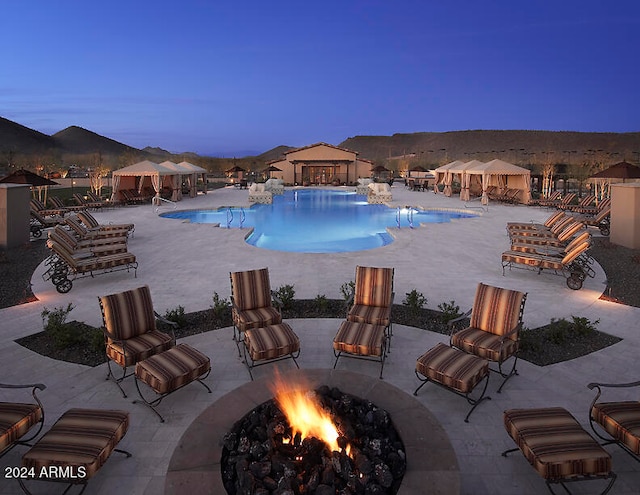 pool at dusk featuring a patio and an outdoor fire pit