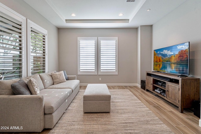 living room featuring light hardwood / wood-style flooring and a tray ceiling