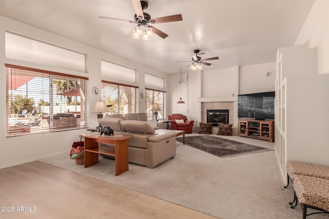 living room with ceiling fan, light wood finished floors, and a tile fireplace