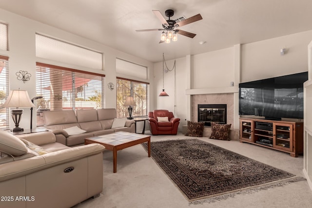 living area featuring light carpet, ceiling fan, and a fireplace