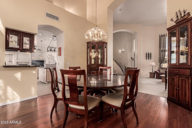 dining area featuring dark wood-style floors, stairway, visible vents, and arched walkways