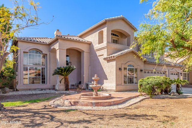 mediterranean / spanish home featuring a tiled roof, a chimney, a garage, and stucco siding