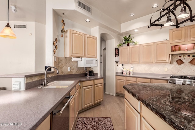 kitchen featuring dark countertops, a sink, visible vents, and pendant lighting