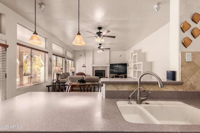 kitchen with a fireplace, hanging light fixtures, open floor plan, a sink, and ceiling fan