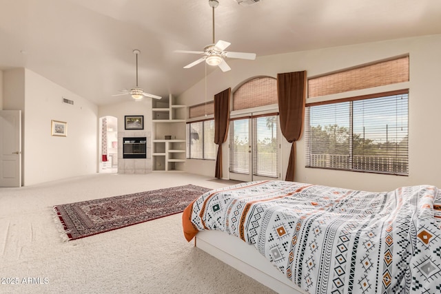 carpeted bedroom featuring vaulted ceiling, a fireplace, visible vents, and a ceiling fan