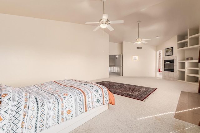 carpeted bedroom with vaulted ceiling, a fireplace, visible vents, and a ceiling fan