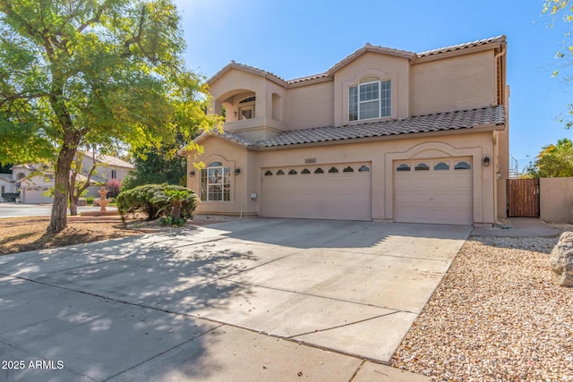 mediterranean / spanish-style house with a tile roof, stucco siding, an attached garage, fence, and driveway