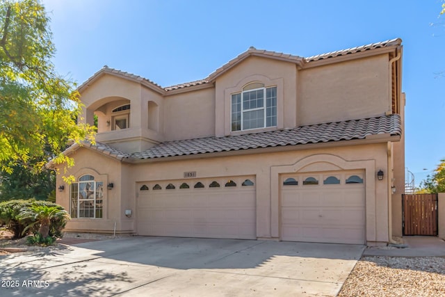 mediterranean / spanish home with an attached garage, driveway, and stucco siding