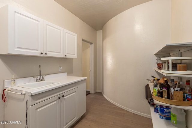 laundry room with light wood-style flooring, baseboards, and a sink