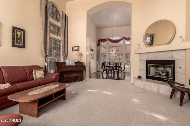 carpeted living area featuring a fireplace and a high ceiling