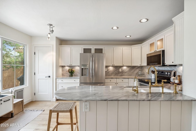 kitchen featuring stainless steel appliances, a peninsula, decorative backsplash, recessed lighting, and light wood-style flooring