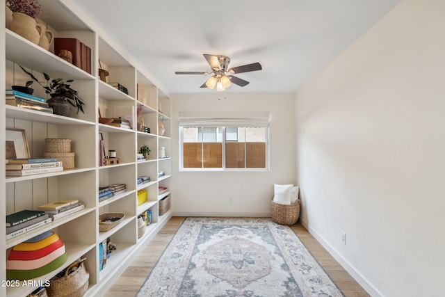 sitting room with a ceiling fan, light wood-type flooring, and baseboards