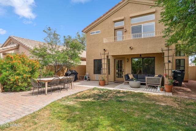 rear view of property featuring a balcony, outdoor lounge area, stucco siding, and a patio
