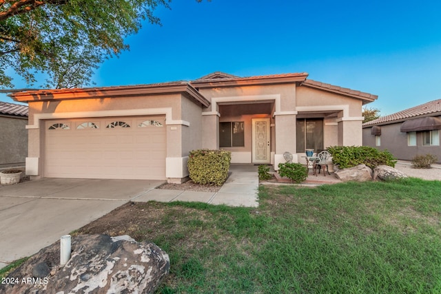 view of front of home with a front yard, driveway, stucco siding, a garage, and a tiled roof