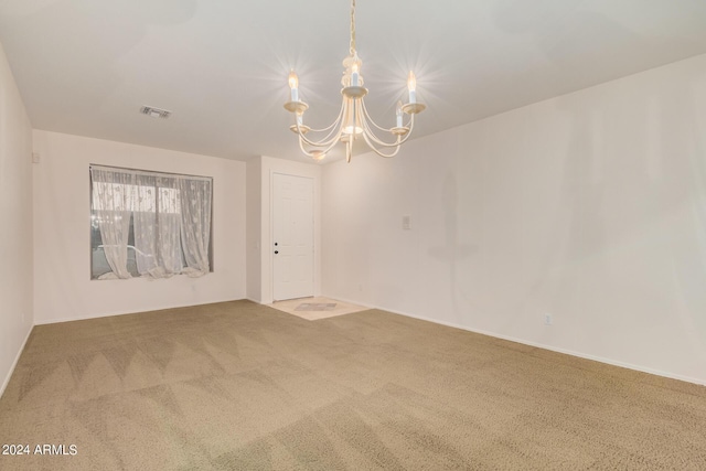 unfurnished room featuring a notable chandelier, carpet flooring, and visible vents