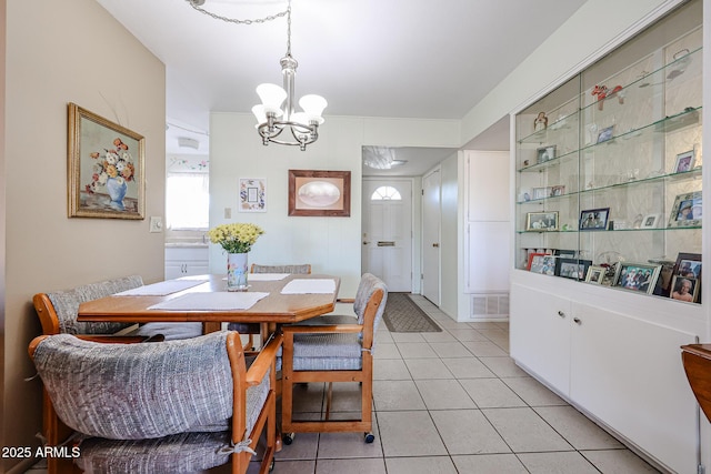 dining space with light tile patterned flooring and an inviting chandelier