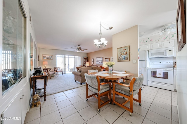 tiled dining space with ceiling fan with notable chandelier