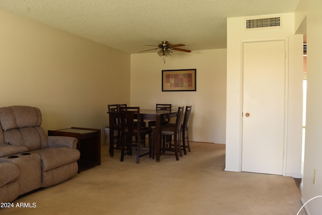 carpeted dining area with ceiling fan and a textured ceiling