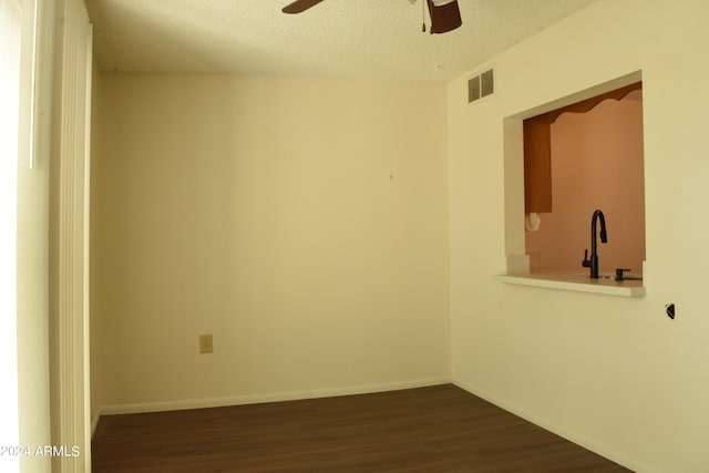 unfurnished room with ceiling fan, a textured ceiling, sink, and dark wood-type flooring