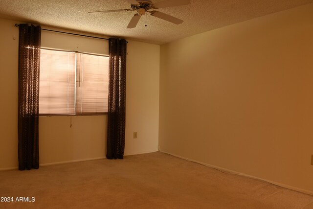 unfurnished room with ceiling fan, carpet flooring, and a textured ceiling