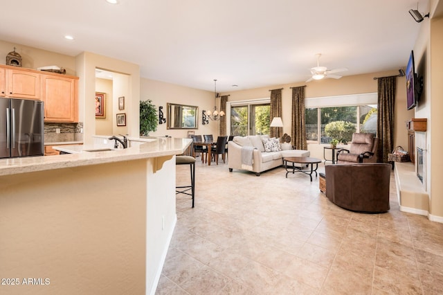 living room featuring sink and ceiling fan with notable chandelier