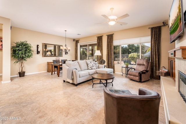 living room featuring ceiling fan with notable chandelier and a high end fireplace