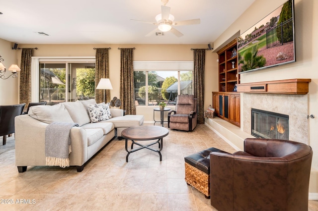 living room with a tile fireplace and ceiling fan