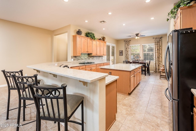 kitchen with a kitchen island, kitchen peninsula, a breakfast bar area, and appliances with stainless steel finishes