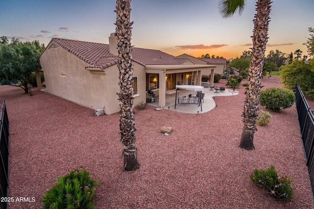 back house at dusk featuring a patio