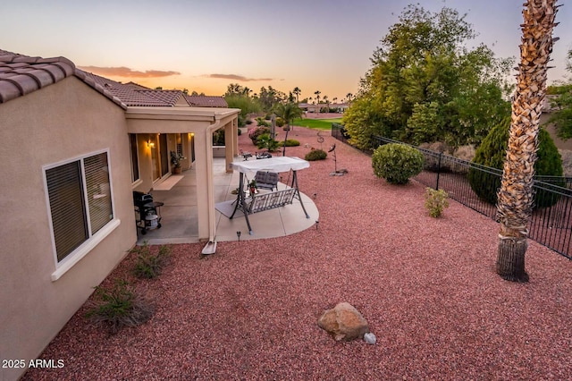 yard at dusk featuring a patio area