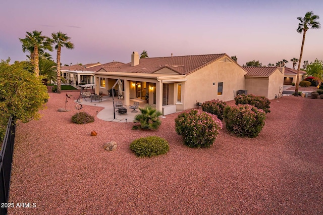 back house at dusk featuring an outdoor fire pit and a patio