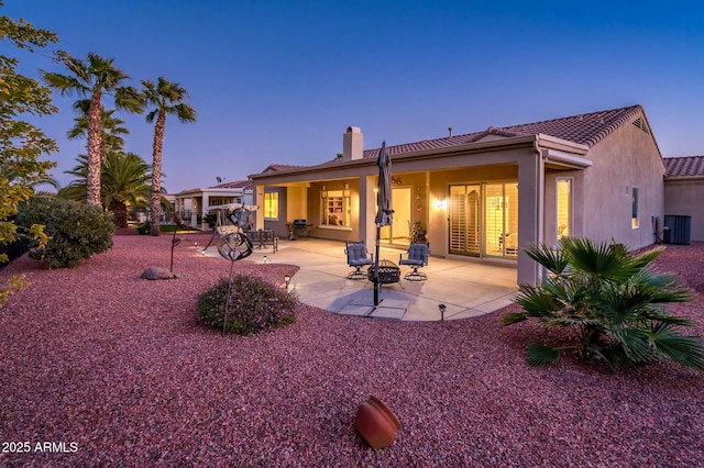 back house at dusk featuring a patio and central AC