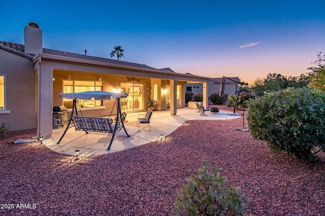 back house at dusk with a patio