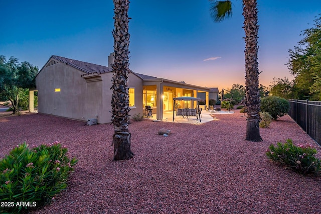 back house at dusk with a patio