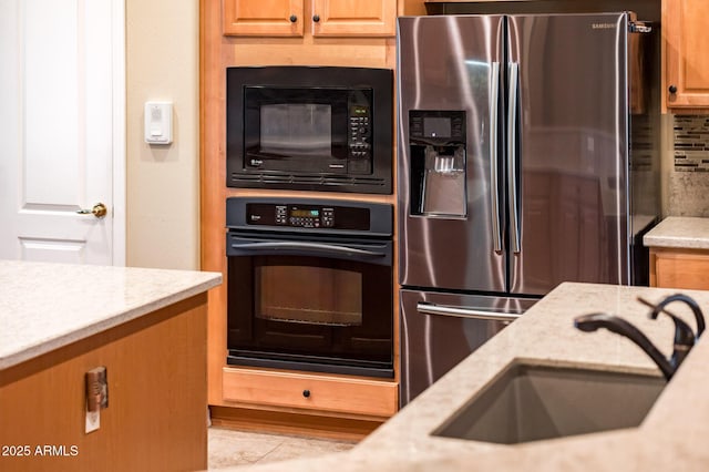 kitchen with sink, tasteful backsplash, light stone counters, and black appliances