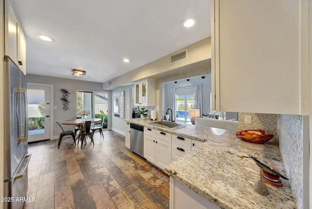 kitchen featuring a sink, stainless steel appliances, glass insert cabinets, recessed lighting, and wood finished floors