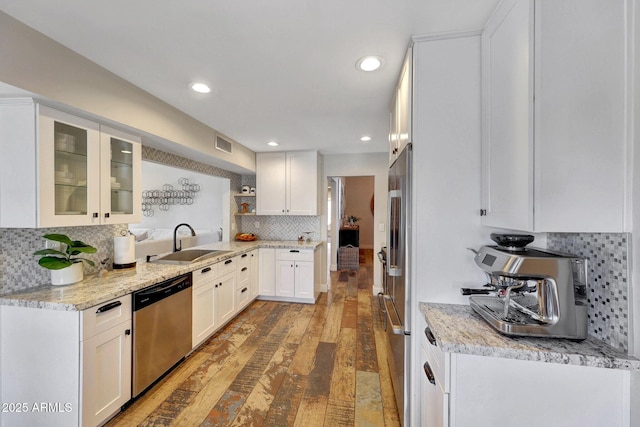 kitchen with stainless steel appliances, a sink, tasteful backsplash, light wood-style floors, and white cabinets