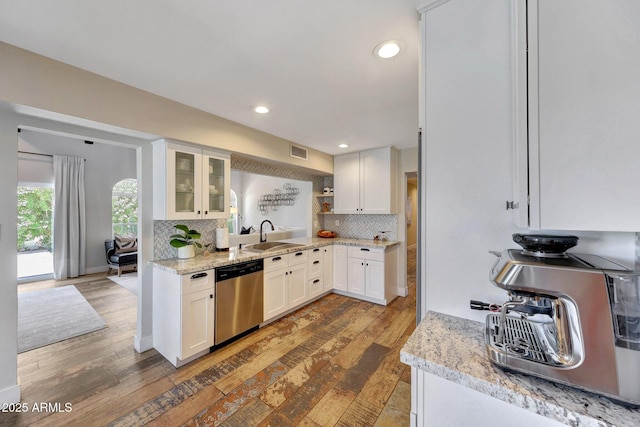 kitchen featuring stainless steel dishwasher, hardwood / wood-style floors, a sink, decorative backsplash, and recessed lighting