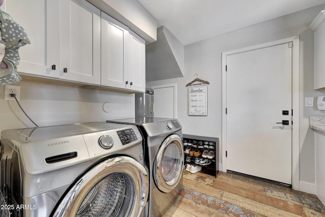 laundry area featuring cabinet space, washing machine and clothes dryer, and light wood finished floors