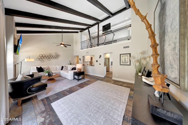 living area featuring ceiling fan, beamed ceiling, baseboards, wood finished floors, and high vaulted ceiling