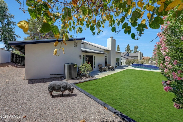 back of house with stucco siding, a chimney, a patio, and central AC